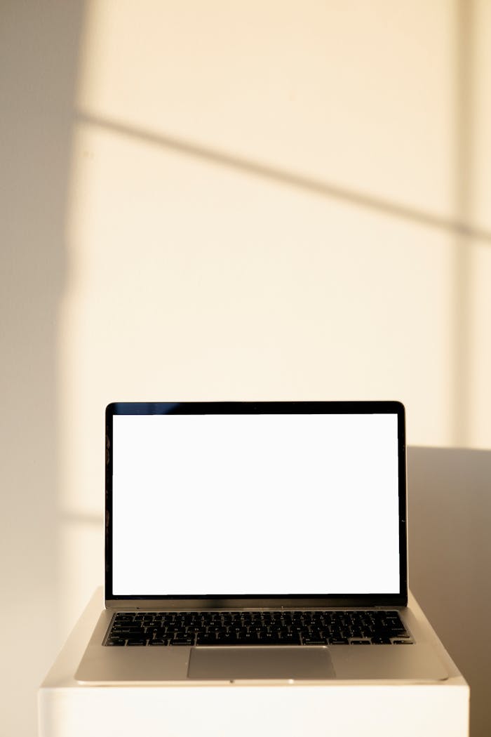 services-03 A sleek laptop with a blank screen, perfect for mockups, set against a sunlit wall for a minimalist aesthetic.